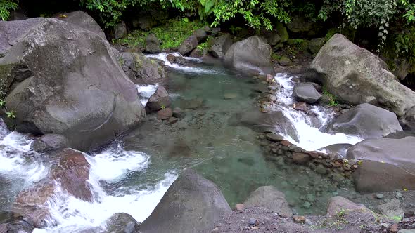 small waterfalls pouring in and out of a shallow pool of clear, refreshing mountain water with bould