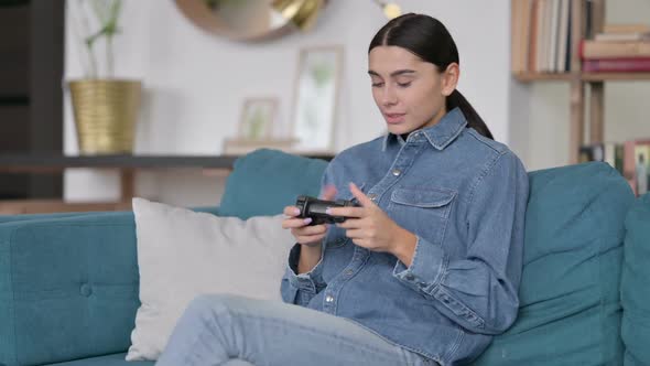 Latin Woman with Success on Video Game on Sofa