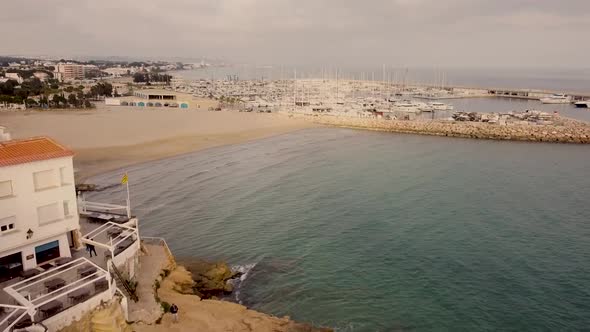 Aerial View Of Roc De Sant Gaieta With Waves On Empty Beach. Dolly Forward