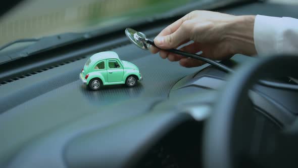 Technician Examining Toy Car With Stethoscope, Vehicle Insurance, Maintenance