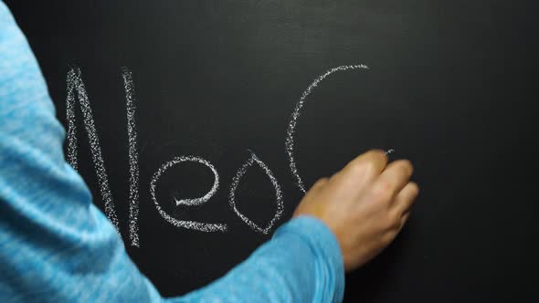 A man's hand writes the word NeoCoV in white chalk on a black board