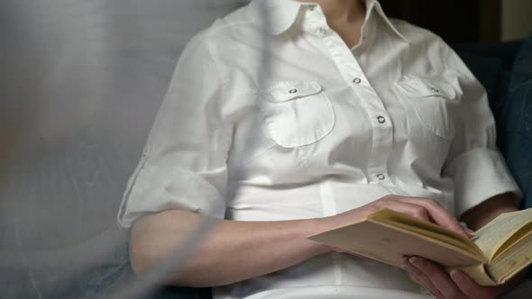 woman reads an old book, household fan works. woman with fan.