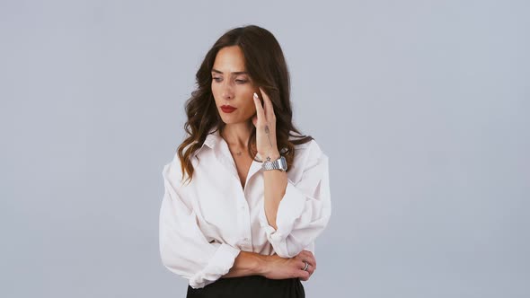 Lady in White Shirt is Looking Nervous Thinking About Something Touching Face and Rubbing Her Hands