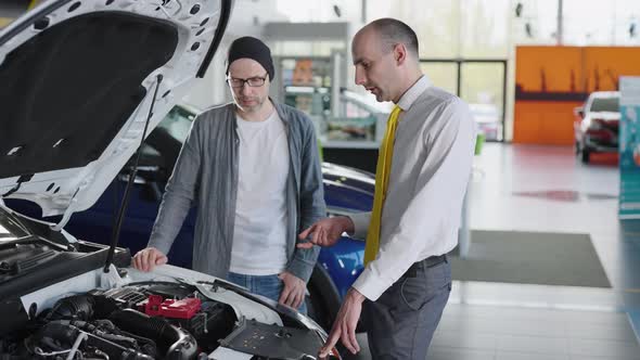 Sales Manager and Client Near a New Car with an Open Hood