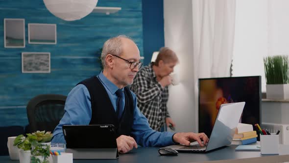 Senior Man Using Laptop and Tablet in Same Time