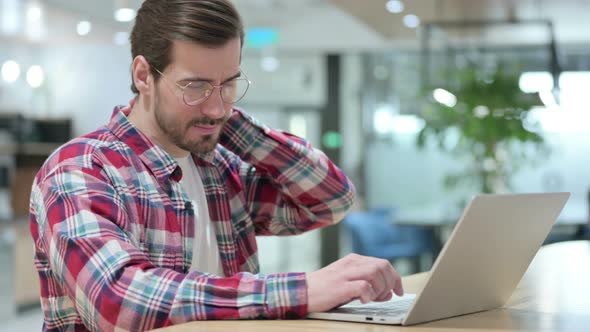 Tired Male Designer with Laptop Having Neck Pain 