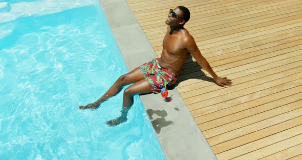 High angle viewof black man rlaaxing with his feet in swimming pool 4k