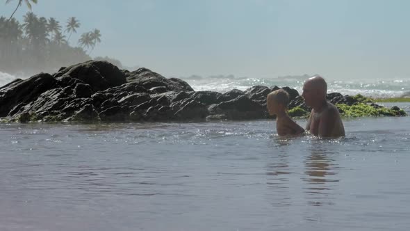 Daddy Helps Son Jump in Calm Sea Water at Exotic Resort