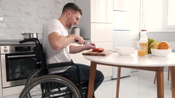 Disabled Young Man in Wheelchair Preparing Food In Kitchen