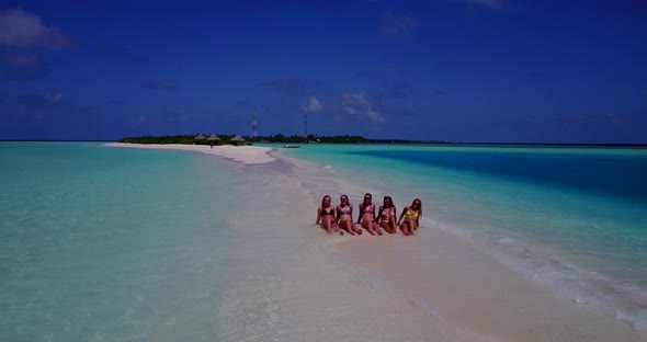 Young smiling girls on holiday in the sun on beach on summer white sandy and blue background 4K