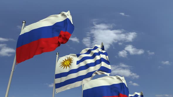 Flags of Uruguay and Russia Against Blue Sky