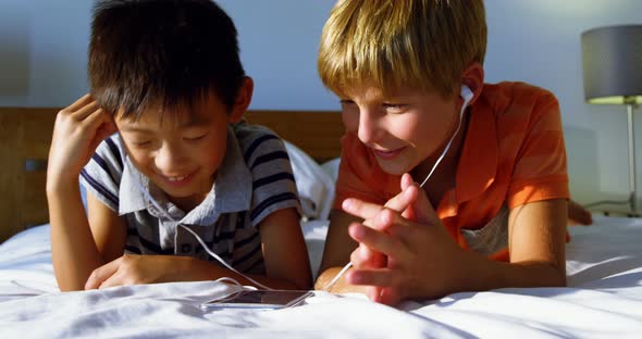 Siblings using mobile phone in bedroom