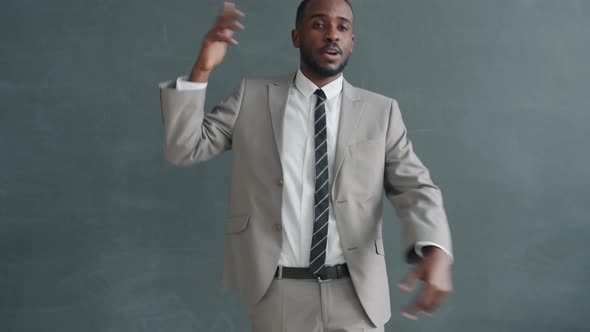 Slow Motion Portrait of African American Businessman in Suit Dancing Against Dark Grey Color
