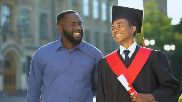 Proud Glad Father Hugging Graduating Son With Diploma, Education Degree, Success