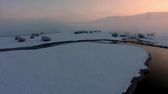 Flying though and over fog during colorful winter sunrise