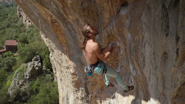 Muscular Man Rock Climber Hangs on Rope on Overhanging Crag Chalks His Hands and Gets Ready to Climb