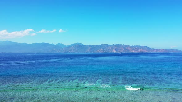 Wide angle birds eye island view of a paradise sunny white sand beach and aqua blue ocean background