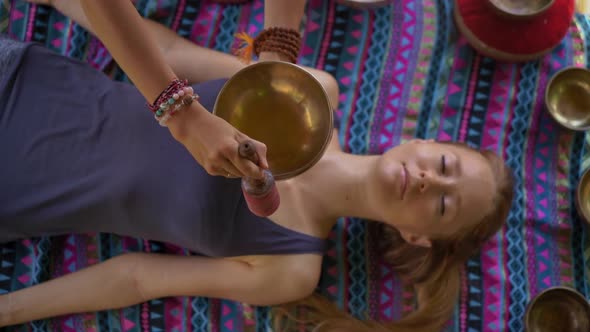 Superslowmotion Shot of a Woman Master of Asian Sacred Medicine Performs Tibetan Bowls Healing