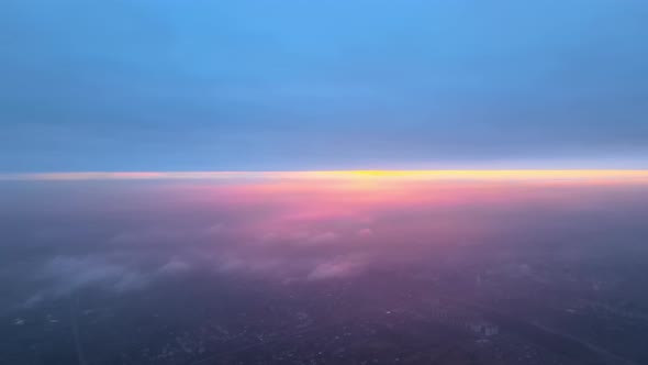 Aerial View From Airplane Window at High Altitude of Distant City Covered with Layer of Thin Misty