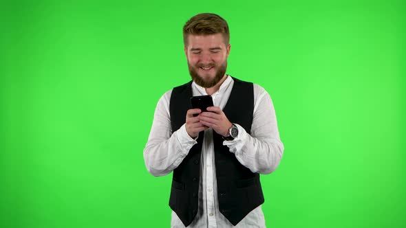 Smiling Man Texting on His Phone on Green Screen.