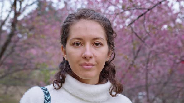 Closeup Portrait of Pretty Girl in Park with Blooming Japanese Sakura Trees