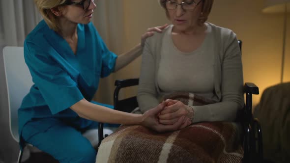 Nurse Talking Heartily to Old Woman in Wheelchair Supporting Her, Elderly Home