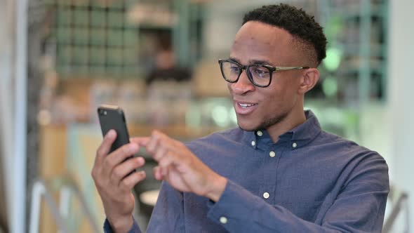 African Man Celebrating Success on Smartphone 