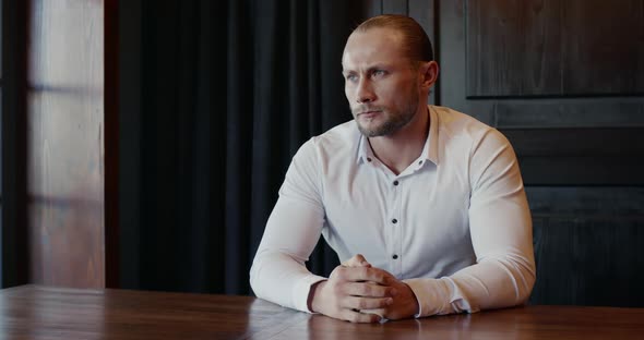 Nervous Handsome Man in Shirt Sat at Table Fidgeting