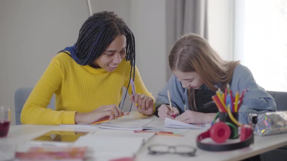 Positive Caucasian Girl Talking To African American Female Friend. Happy Students Doing Homework