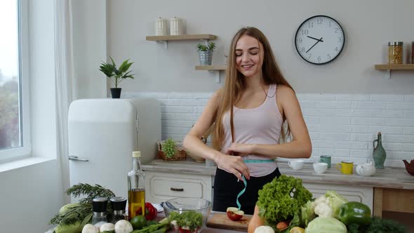 Pretty Girl Eating Juicy Apple. Girl Measuring with Tape Measure Her Slim Waist and Braging