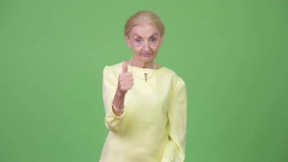 Senior Businesswoman with Blond Hair Giving Thumbs Up