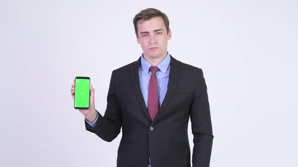 Young Happy Handsome Businessman Showing Phone and Giving Thumbs Up