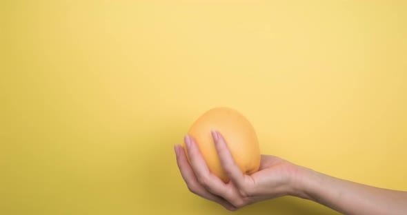 Female hand toss up ripe grapefruit