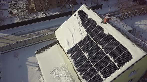 Closeup surface on a house roof covered with solar panels in winter with snow on top.