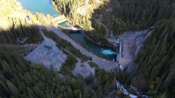 Descending aerial footage of water generating station in the Canadian Rocky Mountains with low sun.