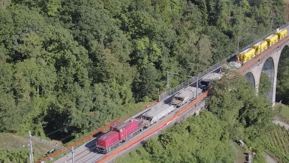 Aerial view of freight train laying ballast passing slowly over viaductPont de Bory, Lavaux - Switz