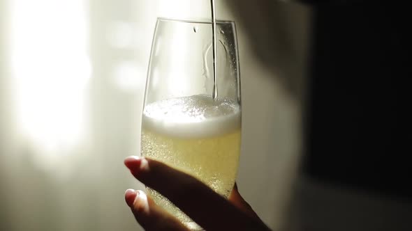 Champagne is Poured From Bottle Into Glass
