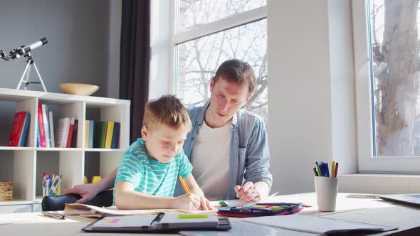 Boy and Father Doing Homework at the Table. Child is Learning at Home.