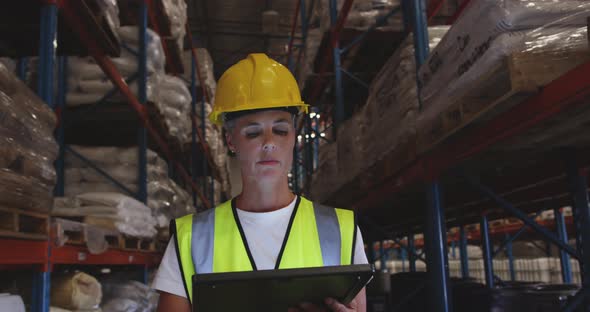 Female warehouse worker patrolling warehouse corridor at night 4k