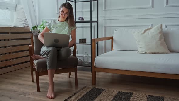 Young Woman Using Laptop Typing Sitting in a Chair Remote Work Work at Home