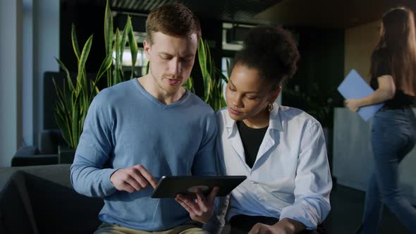 Two Colleagues are Trained on a Tablet While Sitting During Working Hours