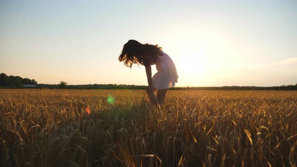 Pretty Woman in White Dress Walking Through Field of Wheat at Sunset