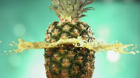 Fresh Pineapple Fruit Squirting and Burst with Juice in Slow Motion in Turquoise Blue Background