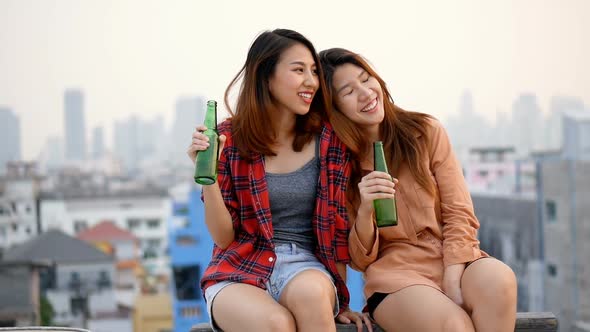 Young Asian woman lesbian couple clinking bottles of beer party on the rooftop.