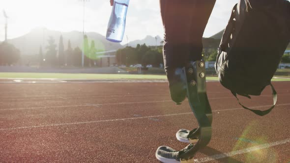 Disabled mixed race man with prosthetic legs walking on a race track