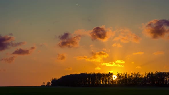 Landscape timelapse with forest, sunset and expressive sky with more bluish graded clouds drifting