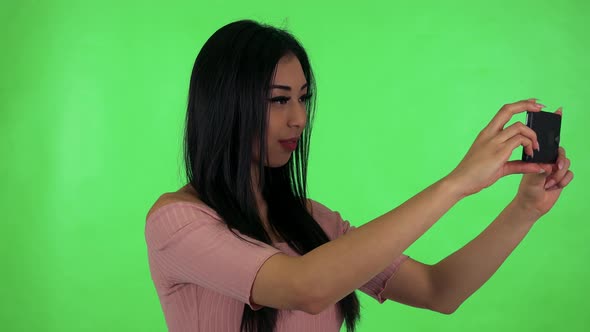 Young Attractive Asian Woman Photographs with Smartphone - Green Screen Studio