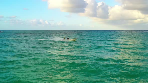 Small narrow motor boat carrying three people travels on green ocean sea waters, Punta Cana, Dominic