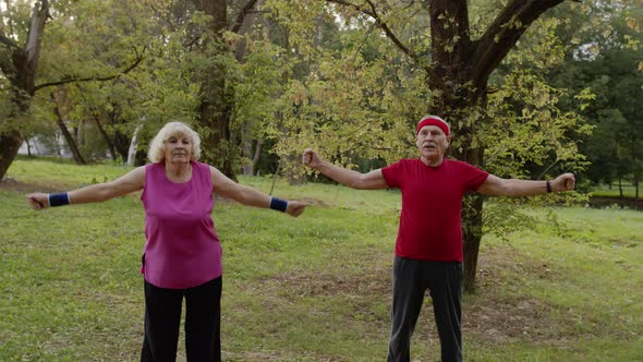 Senior Active Couple Doing Sport Physical Exercises Outdoor in City Park. Morning Stretching Workout