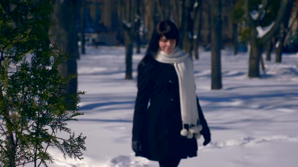 Pretty Brunette Female Walks Smiling In Snow Covered Park. Winter City Life Background Slow Motion